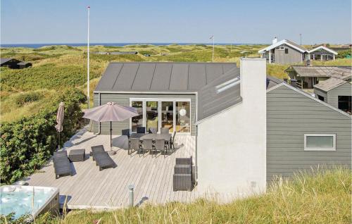 a house with a deck with chairs and an umbrella at Five-Bedroom Holiday Home Løkken With A Room Hot Tub 04 in Løkken