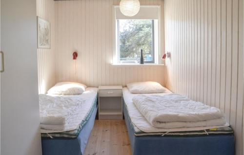 Duas camas num pequeno quarto com uma janela em Lrken em Vejers Strand
