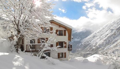 a building covered in snow next to a tree at Chalet Broski - Luxury near St Martin De Bellville in Planvillard
