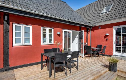 a deck with a black table and chairs next to a red house at 2 Bedroom Lovely Apartment In Aakirkeby in Åkirkeby