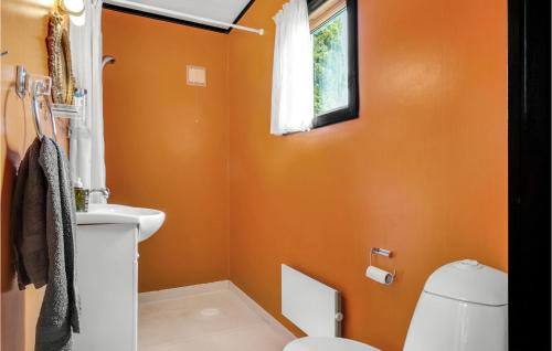 a bathroom with orange walls and a toilet and a window at Lovely Home In Sjllands Odde With Wifi in Tjørneholm