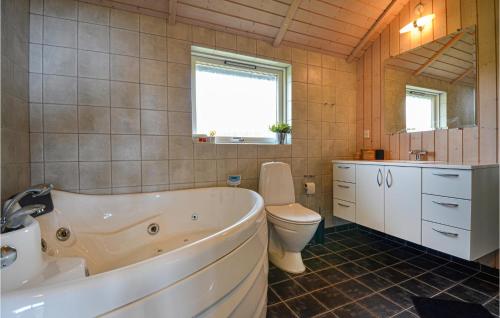 a bathroom with a tub and a toilet and a sink at Nice Home In Glesborg With House Sea View in Bønnerup Strand