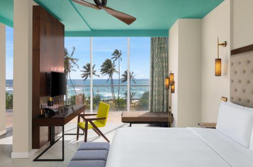 a hotel room with a bed and a desk with a view at Radisson Blu Resort Galle in Galle