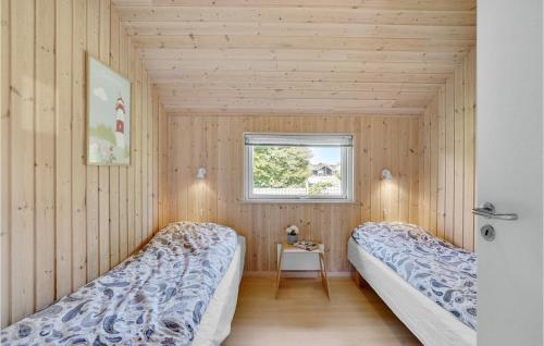 2 camas en una habitación con paredes de madera y ventana en Amazing Home In Idestrup With Kitchen, en Bøtø By