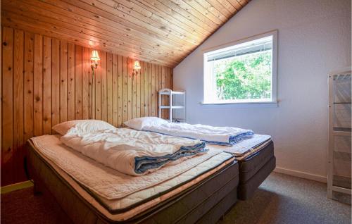 two beds in a room with a wooden wall at Stunning Home In Rnde With 3 Bedrooms And Wifi in Rønde