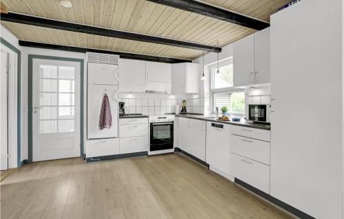 a kitchen with white cabinets and a wooden floor at Holiday Home Romo Lxviii in Bolilmark