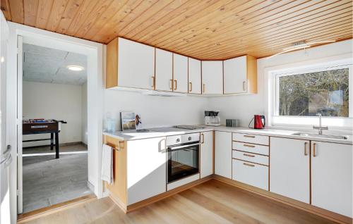 a kitchen with white cabinets and a wooden ceiling at Amazing Home In Nørre Nebel With Wifi in Nørre Nebel