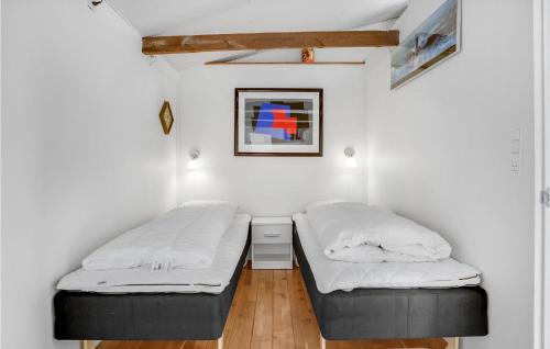 two beds in a room with white walls and wooden floors at Holiday Home Holbæk 39 With Hot Tub in Holbæk