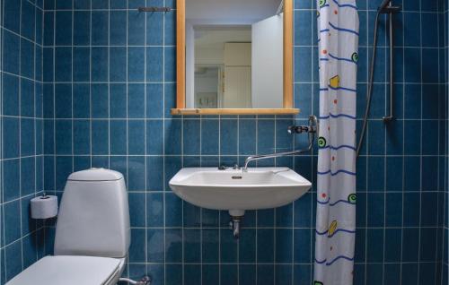 a blue tiled bathroom with a toilet and a sink at Terrassehus in Fæbæk