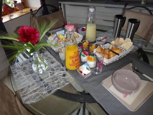 einen Tisch mit einer Vase Blumen und einem Tablett mit Essen in der Unterkunft La maison du Fargis in Auffargis