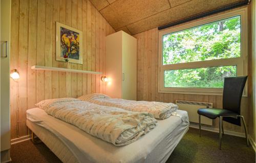 a bedroom with two beds and a chair and a window at Beautiful Home In Glesborg With Sauna, Wifi And Outdoor Swimming Pool in Fjellerup Strand