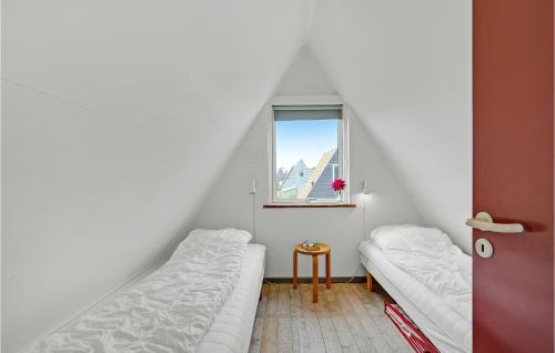 ゲッサーにあるCozy Home In Gedser With Wifiのベッド2台と窓が備わる小さな客室です。