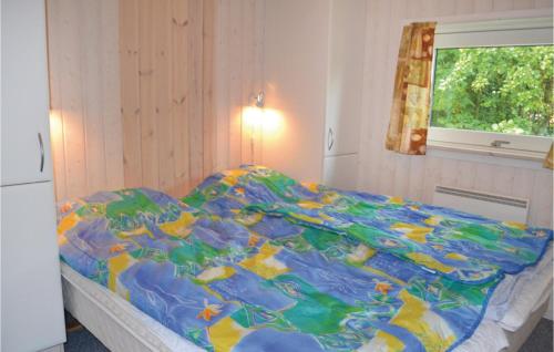 a bed with a colorful comforter in a bedroom at Awesome Home In Oksbl With Sauna in Ovtrup