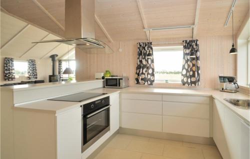 a kitchen with white cabinets and a stove top oven at Three-Bedroom Holiday Home In Vaggerlose in Marielyst