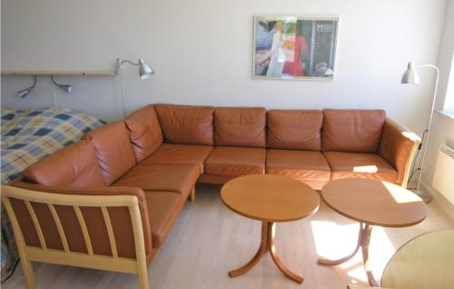 a brown leather couch in a living room with two tables at Mlleparken in Gudhjem