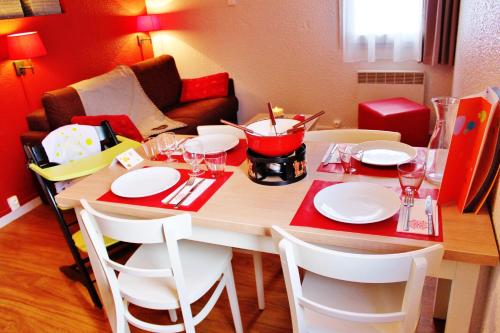 a dining table with white plates and a red table at VVF La Plagne Montchavin Paradiski in Bellentre