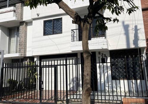 una casa blanca con una valla negra y un árbol en Casa Salmón Confortable Casa Completa en Valledupar