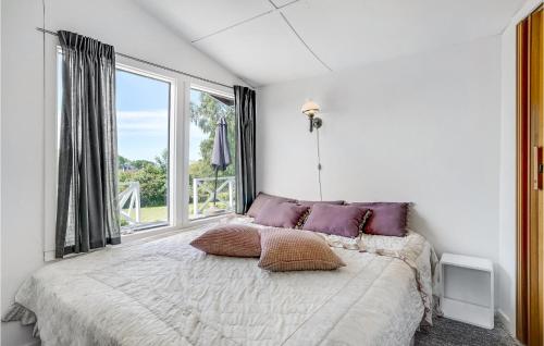 a bedroom with a bed with pillows and a window at Beautiful Home In Vordingborg With House Sea View in Bakkebølle Fredskov