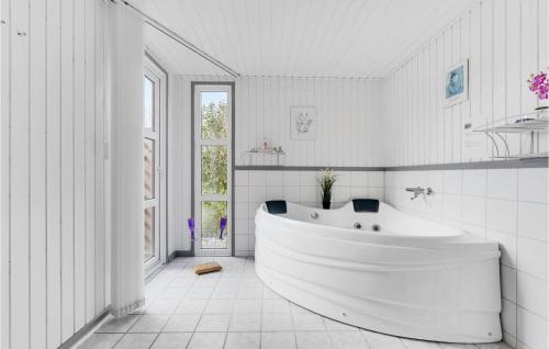 SkovbyにあるLovely Home In Sydals With Saunaの白いバスルーム(バスタブ付)、窓が備わります。