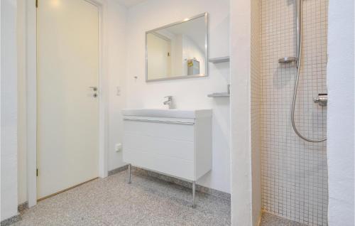 een witte badkamer met een wastafel en een spiegel bij Cozy Home In Fan With Kitchen in Fanø