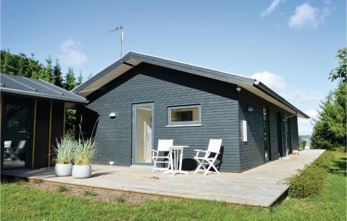 a black tiny house with a deck and two chairs at Three-Bedroom Holiday Home In Skals in Skals