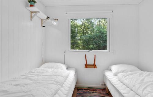 two beds in a white room with a window at Amazing Home In Aakirkeby With House Sea View in Vester Sømarken