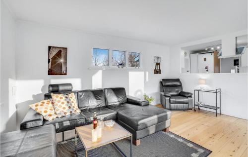 a living room with a black leather couch and a table at Awesome Home In Holbæk With Kitchen in Holbæk