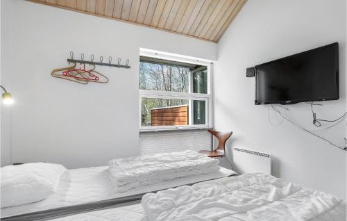 a bedroom with a bed and a flat screen tv at Rubinsen Skovhuse in Tofte