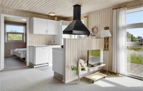 Bjerregårdにある3 Bedroom Amazing Home In Hvide Sandeの白いキャビネットと薄型テレビ付きのキッチンが備わります。