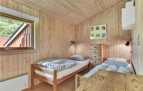 two beds in a wooden room with a table at Paradiset in Skattebølle