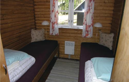 two beds in a log cabin with a window at Stunning Home In Nex With 2 Bedrooms And Wifi in Spidsegård