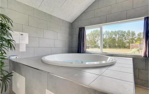a large tub in a bathroom with a large window at Amazing Home In Vggerlse With Sauna in Marielyst