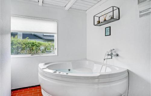 Fjellerup StrandにあるAmazing Home In Glesborg With 4 Bedrooms, Sauna And Wifiの白いバスルーム(バスタブ付)、窓が備わります。