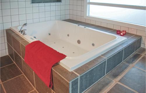 a bath tub with a red towel in a bathroom at Lovely Home In Hvide Sande With Private Swimming Pool, Can Be Inside Or Outside in Havrvig