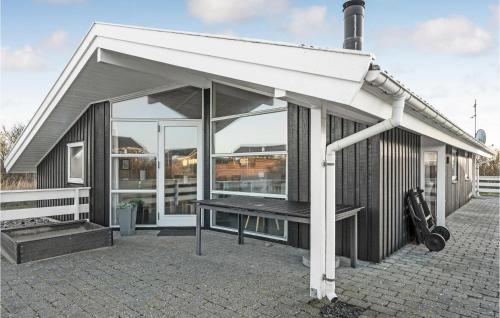 un edificio con una tenda da sole e una panchina su un patio di Holiday Home Lakolk Ic Denmark a Bolilmark