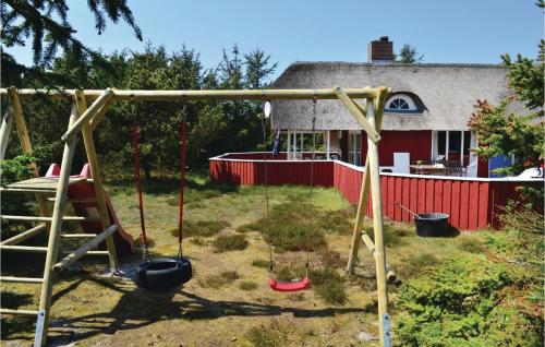 einen Spielplatz mit Schaukeln und ein Haus im Hintergrund in der Unterkunft Holiday Home Hvide Sande 1146 in Bjerregård