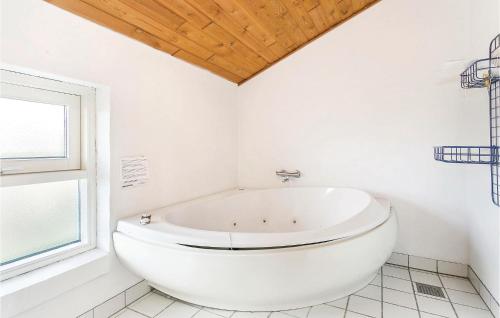 a white bath tub in a white bathroom with a window at Stunning Home In Thisted With Sauna in Klitmøller