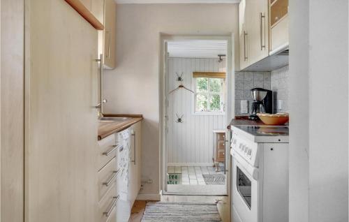 Awesome Home In Knebel With Kitchen في Skødshoved Strand: مطبخ مع دواليب بيضاء وباب يؤدي الى الممر