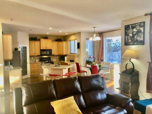 sala de estar con sofá de cuero y cocina en 2500 sq house in Springbank Hill BL 261818 en Calgary
