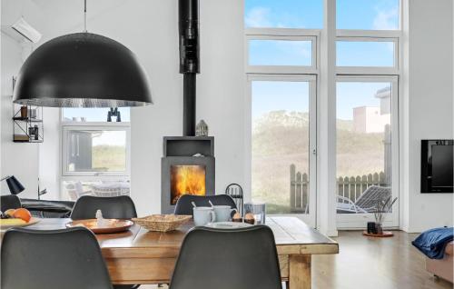 a dining room with a table and a fireplace at 3 Bedroom Gorgeous Home In Blokhus in Blokhus
