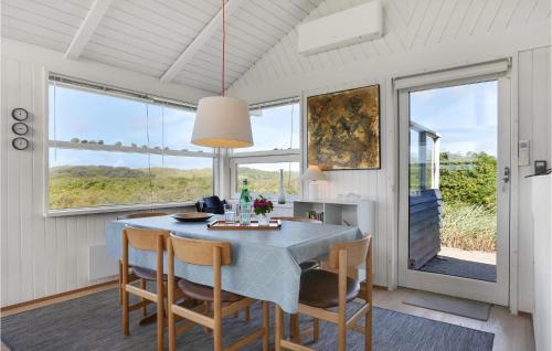 a dining room with a table and chairs and windows at Pynten in Grønhøj