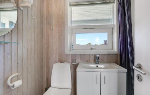 a bathroom with a toilet and a sink and a window at Pynten in Grønhøj