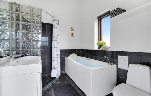 a bathroom with a tub and a toilet and a sink at Nice Home In Rm With 2 Bedrooms And Wifi in Bolilmark