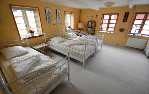 SkattebølleにあるAwesome Home In Tranekr With 4 Bedroomsの黄色の壁と窓が特徴の客室で、ベッド2台が備わります。