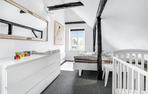 ein weißes Zimmer mit einem Kinderbett und einem Bett in der Unterkunft Cozy Home In Glesborg With Kitchen in Bønnerup Strand