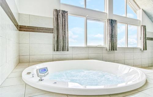 a large white tub in a bathroom with windows at Nice Home In Bogense With Sauna, Wifi And Indoor Swimming Pool in Bogense