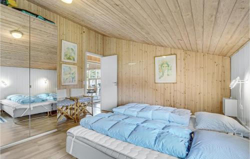 a bedroom with a bed and a wooden wall at Amazing Home In Ringkbing With 5 Bedrooms, Sauna And Wifi in Klegod