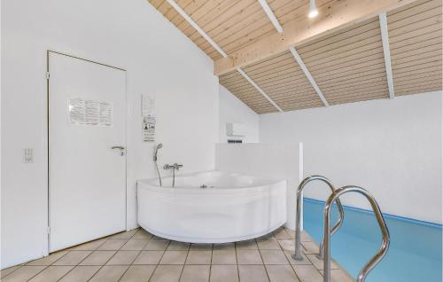 a white bathroom with a tub in a room at Awesome Home In Juelsminde With 4 Bedrooms, Sauna And Wifi in Sønderby