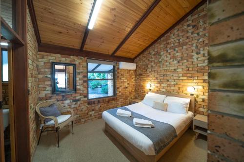 a bedroom with a bed and a brick wall at Blickinstal Holiday Retreat in Bethany