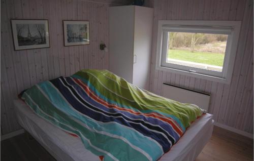 uma cama com um cobertor colorido num quarto com uma janela em 3 Bedroom Awesome Home In Tranekr em Skattebølle